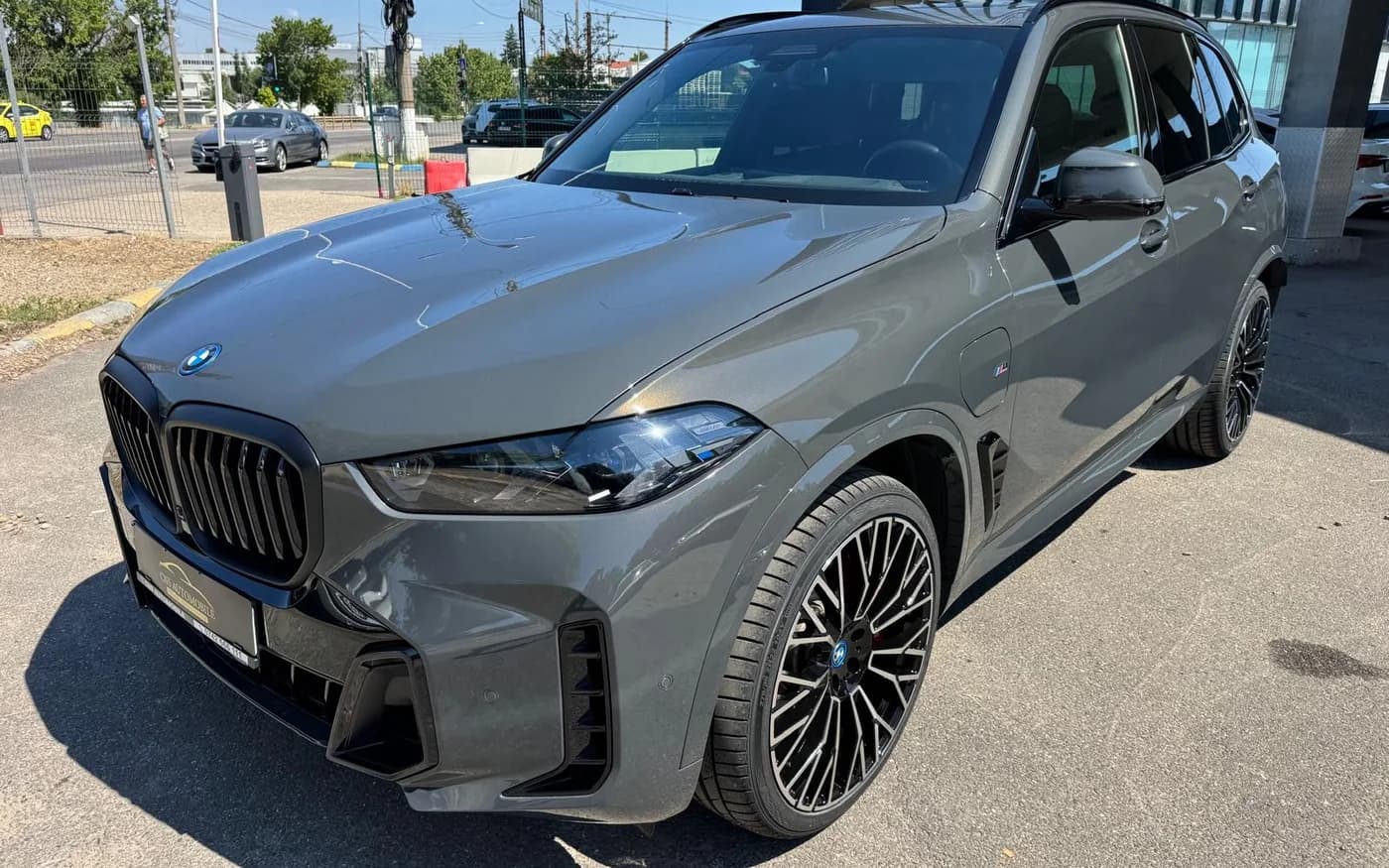 A grey BMW X5 photographed on a dealer forecourt before AutoStudio